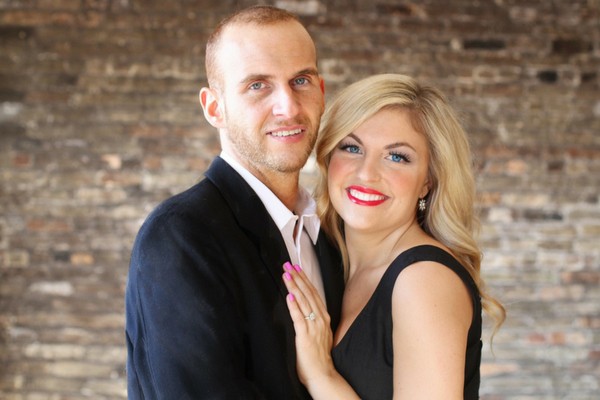 Man and Woman posing for a picture presenting engagement ring